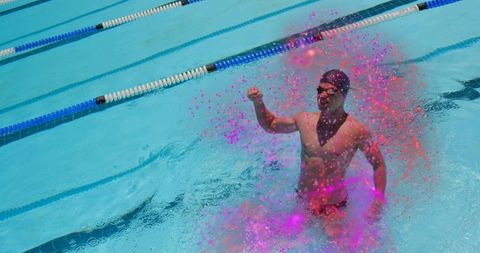 Swimmer celebrates with vibrant pink splash in pool