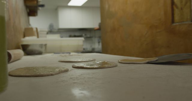 Raw dough circles on a floured kitchen surface ready for baking. Ideal for illustrating bakery processes, cooking tutorials, or homemade bread recipe articles. Suitable for food blogs, culinary magazines, and educational materials.