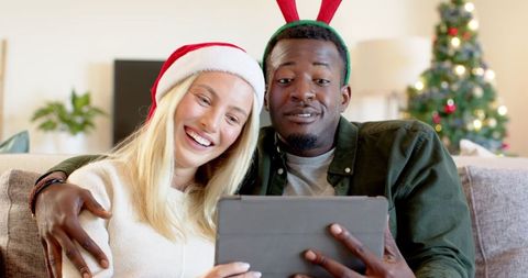 Joyful Couple Celebrating Christmas on Sofa with Tablet
