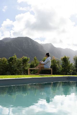 Relaxing by pool with mountain view — middle-aged asian woman sitting on bench