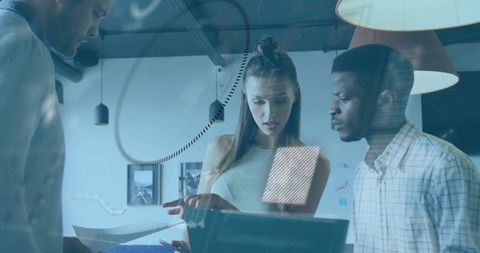 Team collaborating over laptop and documents with glass reflections in modern coworking space