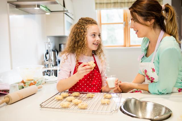 Daughter interacting with mother while having cookies in the kitchen at home