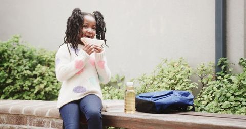 Happy child enjoying sandwich outdoors on a bench