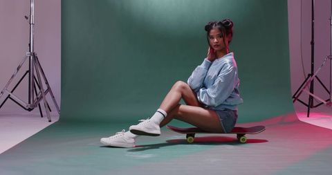 Fashionable teen skater posing in studio with green backdrop