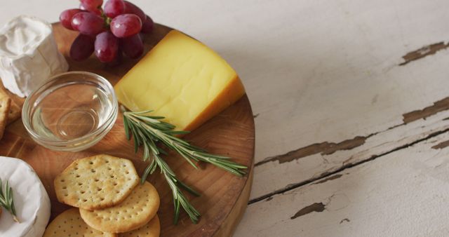 Image of cheese, biscuits, grapes and rosemary on wooden board and rustic table top with copy space. quality, tasty light food snack.
