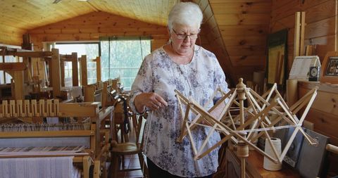 Senior woman engaging in traditional textile spinning at home