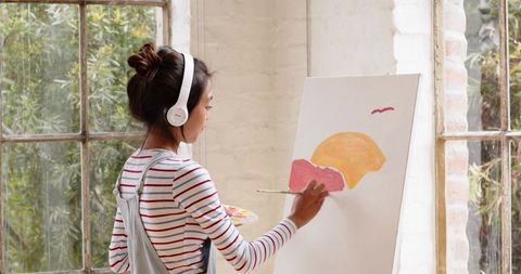 Creative Female Painter Painting Shapes at Studio Easel with Headphones