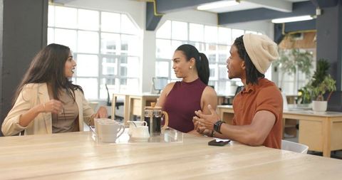 Diverse team discussing ideas over coffee in modern open-plan coworking hub