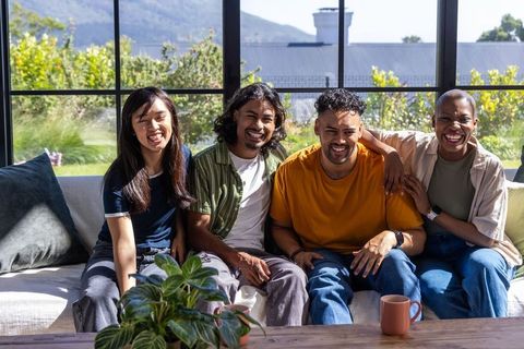 Diverse friends laughing together on sofa in bright modern living room