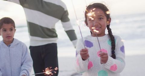Young Girl Celebrating with Sparklers on Beach at Sunset