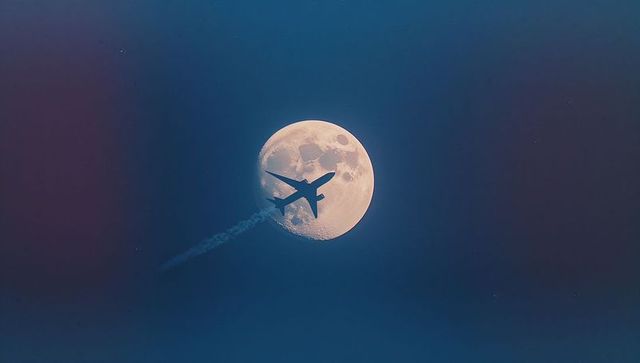 Silhouette of Airplane Crossing Waxing Gibbous Moon in Twilight
