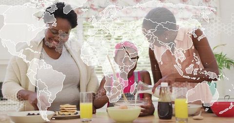 Multigenerational family preparing pancakes in sunlit kitchen with global map overlay