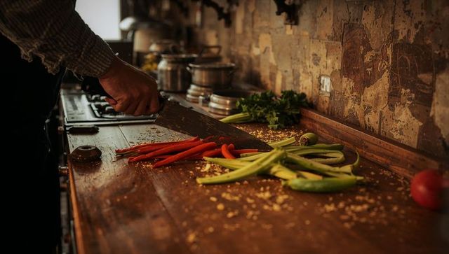 Chef slicing colorful chillies in rustic kitchen setting