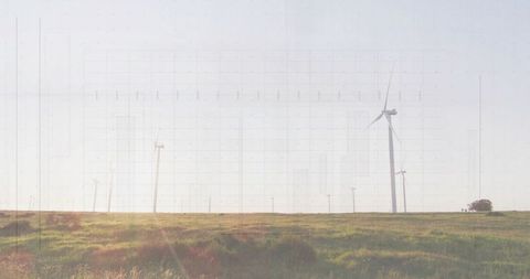 Wind turbine spinning over sunlit grassland with vintage lens flare and open sky