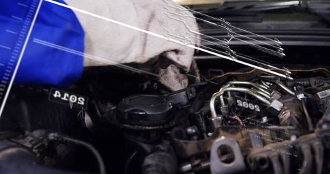 Mechanic wiping gloved hand under car hood during engine maintenance and inspection