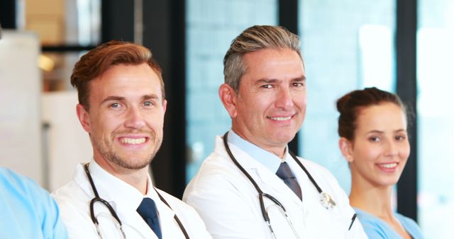 Group of healthcare professionals smiling confidently, wearing medical uniforms and stethoscopes. Ideal for depicting healthcare teams, medical community, hospital environments, and professional medical services.
