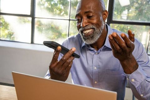 Businessman Engaging in Video Call via Smartphone at Office Desk