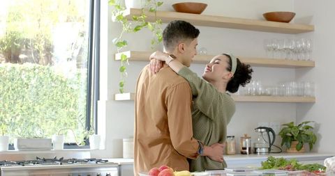 Happy Couple Embracing in Modern Kitchen with Fresh Produce