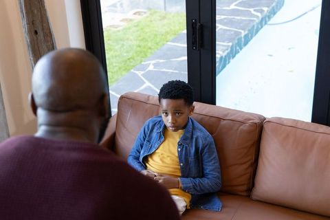 Father having serious talk with son on couch by pool