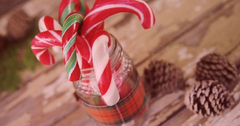 Festive candy canes in plaid ribbon jar on rustic table