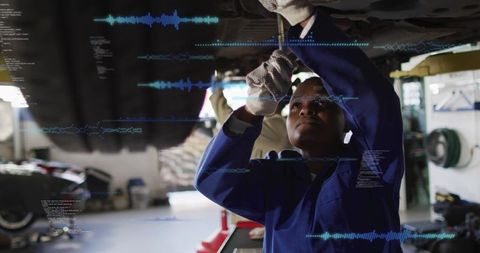 Automotive mechanic inspecting undercarriage using AR diagnostics in modern garage