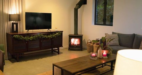 Cozy living room featuring wood-burning stove, tv console and candlelit coffee table