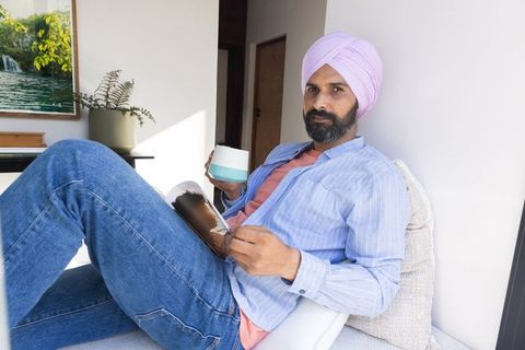 Mid adult indian man relaxing with magazine and coffee
