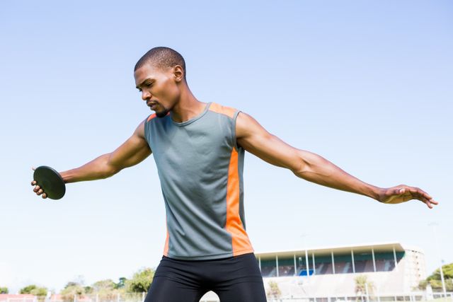 Athlete preparing to throw discus in stadium, showcasing strength and focus. Ideal for use in sports-related content, fitness promotions, athletic training materials, and motivational posters.