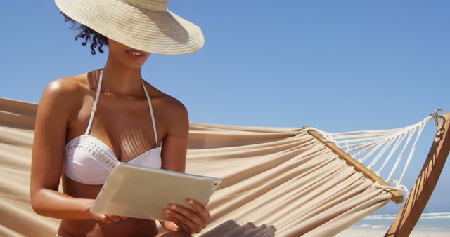 Woman Relaxing on Hammock at Beach with Sun Hat and Tablet - Download Free Stock Images Pikwizard.com