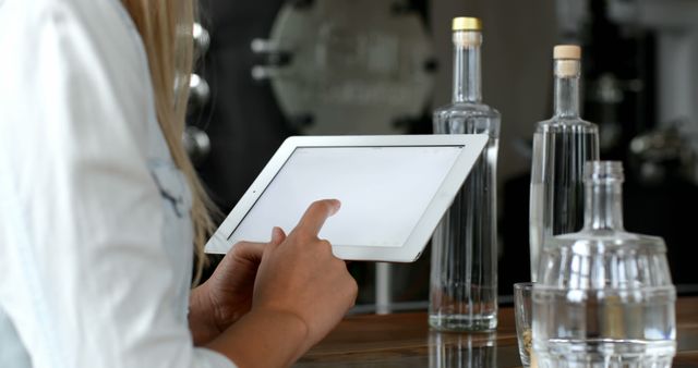 Person Using Tablet in Bar Area with Bottles - Download Free Stock Images Pikwizard.com