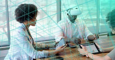 Diverse team exploring augmented reality data with vr headset and tablets in workspace