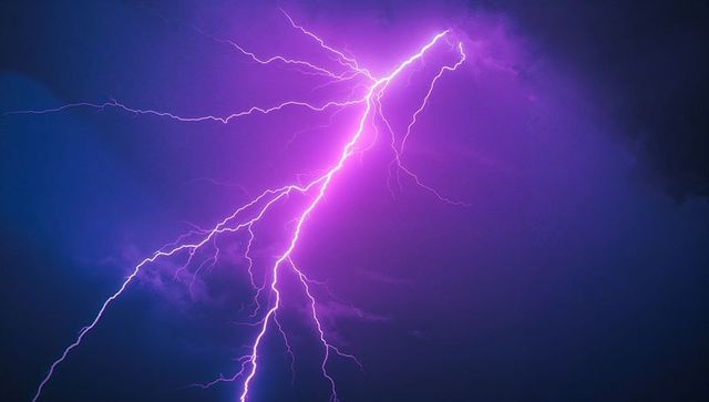 Dramatic Purple Lightning Bolt Against Stormy Night Sky