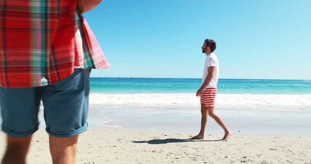 Men walking on beach while talking on mobile phone during summertime 4k