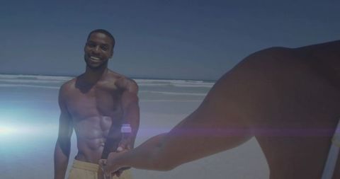 Shirtless Man Smiling While Holding Hands on Sunny Beach