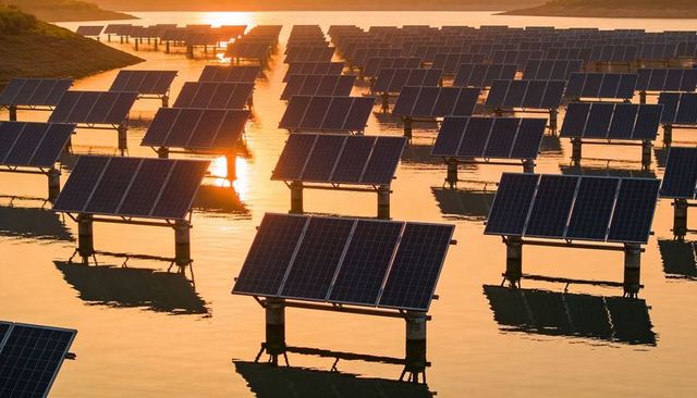 Floating solar panels glowing at golden sunset over reservoir, reflecting on water