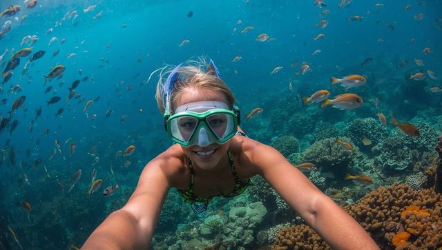 Snorkeling woman taking underwater selfie amid colorful coral reef and tropical fish