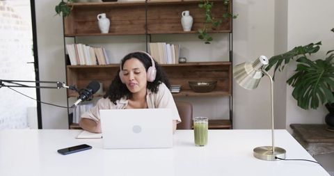 African american woman recording podcast in minimalist workspace with laptop and mic