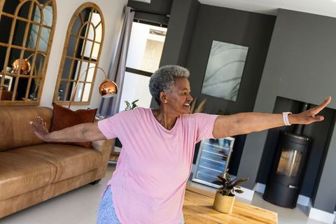 Senior african woman stretching and balancing at home for mobility, posture and wellness