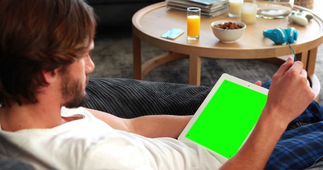 Man Relaxing on Sofa Using Digital Tablet with Green Screen While Wearing Casual Clothes - Download Free Stock Images Pikwizard.com