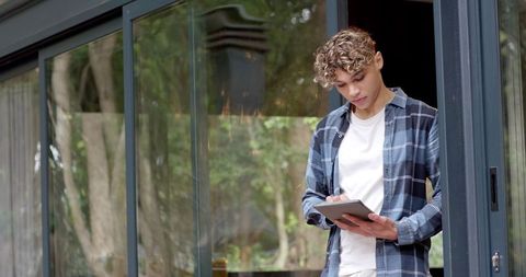 Young innovative professional using tablet stylus near glass door