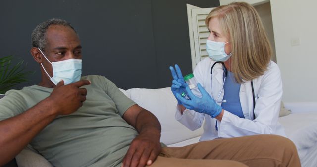 Caucasian senior female doctor talking with male patient in bed both wearing face masks. hygiene healthcare protection during coronavirus covid 19 pandemic.