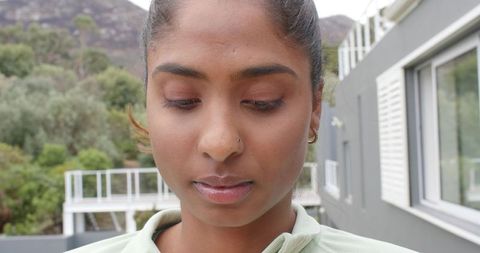 Contemplative indian woman standing on balcony gazing downward nose stud and hoop earring