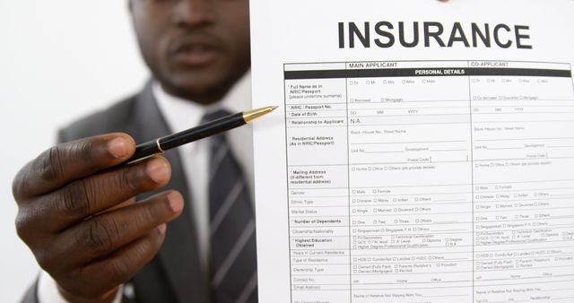 African american businessman holding pen pointin on insurance document with copy space. Insurance, business, finance, work, office and technology concept, unaltered.