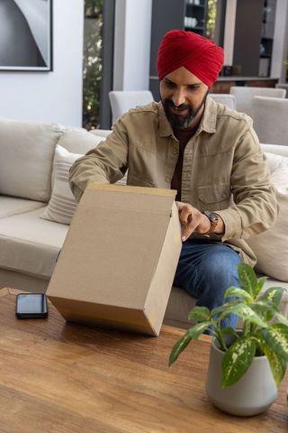 Mid adult indian man unpacking delivery in modern living room