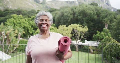 Happy Senior Woman with Yoga Mat Relaxing on Balcony