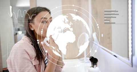 Woman applying lipstick at illuminated vanity mirror with augmented reality globe interface