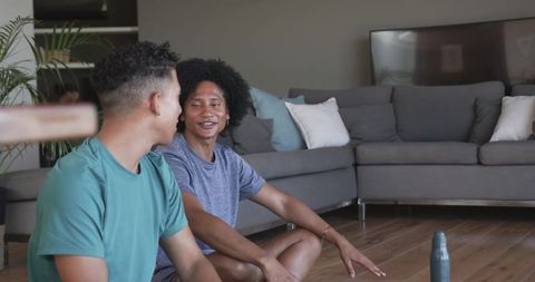Friends chatting on living room floor in casual tees, relaxed home conversation and bonding