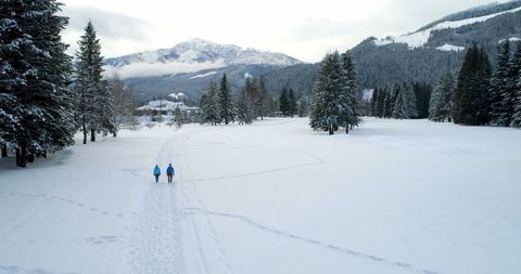 Couple Walking Through Snowy Winter Landscape with Mountain View - Download Free Stock Images Pikwizard.com