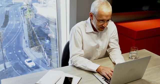 Senior Businessman Working on Laptop in Modern Office with City View - Download Free Stock Images Pikwizard.com