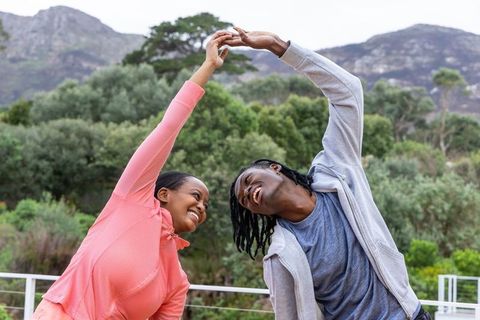African american couple stretching together on outdoor deck with mountain view